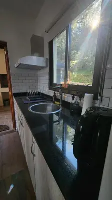 a kitchen with a sink and a large window at Cabañas La Frontera in Villa General Belgrano