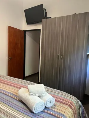 a bedroom with two towels on a bed with a wardrobe at Cabañas La Frontera in Villa General Belgrano