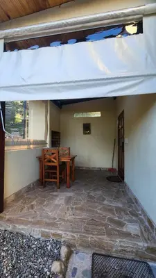 a patio with a wooden table and a white awning at Cabañas La Frontera in Villa General Belgrano