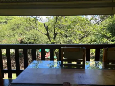 a wooden table and chairs on a porch with a view of a tree at Cabañas La Frontera in Villa General Belgrano