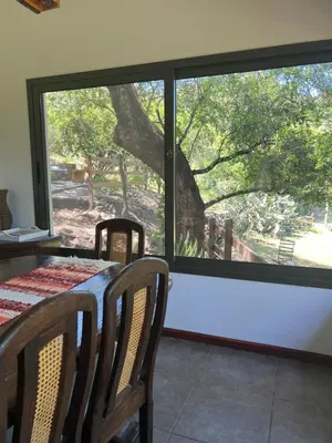 a dining room with a table and a large window at Cabañas La Frontera in Villa General Belgrano