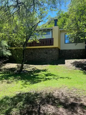 a house with a stone wall and a balcony at Cabañas La Frontera in Villa General Belgrano