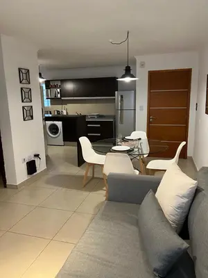 a living room and kitchen with a couch and chairs at Departamento céntrico en Córdoba in Cordoba