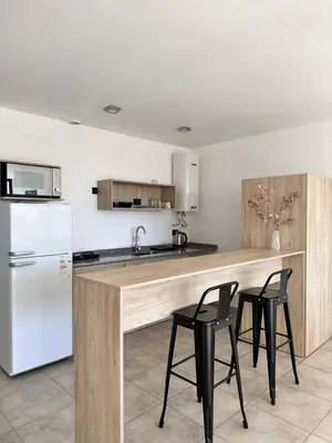 a kitchen with a counter with two chairs and a refrigerator at Departamento Estrada Lux Céntrico in Villa Carlos Paz