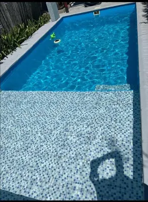a blue tile swimming pool with a persons shadow in the water at Cabañas Las abuelas in Villa Rumipal
