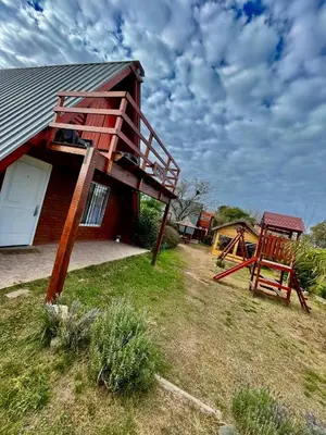 a house with a slide and a playground at Cabañas Las abuelas in Villa Rumipal