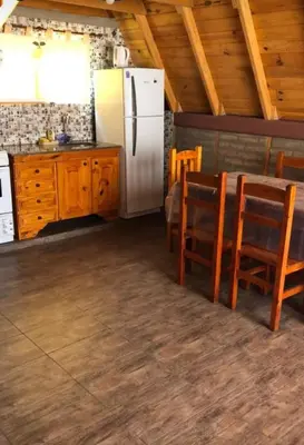 a kitchen with a refrigerator and a table and chairs at Cabañas Las abuelas in Villa Rumipal