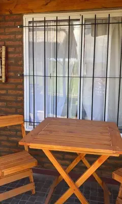 a wooden picnic table and a bench in front of a window at Cabañas Las abuelas in Villa Rumipal
