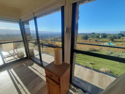 a room with large windows and a table with a vase on it at Mirada al Champaquí - Chalet de Montaña in Villa Yacanto