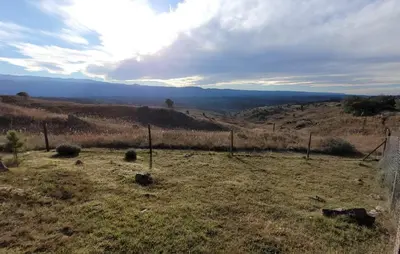 a field with a fence in the middle of a hill at Mirada al Champaquí - Chalet de Montaña in Villa Yacanto