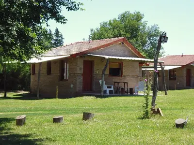 a small brick house with a chair in the yard at Cabanas Parparim in Mina Clavero
