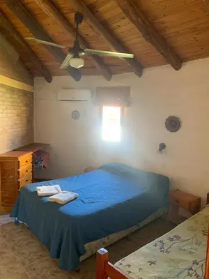 a bedroom with a blue bed and a ceiling fan at Cabanas Parparim in Mina Clavero