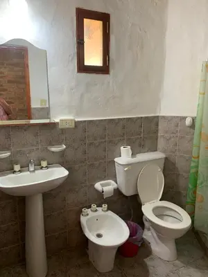 a bathroom with a sink and a toilet and a mirror at Cabanas Parparim in Mina Clavero