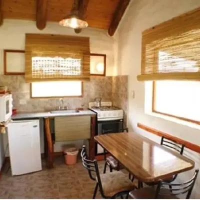 a kitchen with a table and a sink and a stove at Cabanas Parparim in Mina Clavero