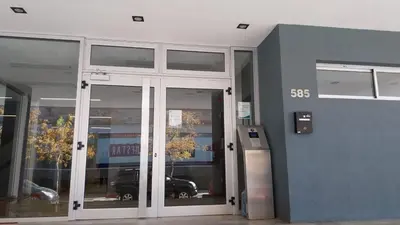a building with glass doors with a car parked inside at Departamento en Edificio Fluss, Mariano Fragueiro 585 in Cordoba