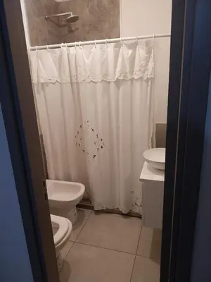 a bathroom with a white shower curtain and a toilet at Departamento en Edificio Fluss, Mariano Fragueiro 585 in Cordoba