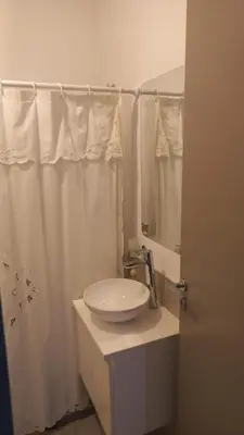 a white bathroom with a sink and a mirror at Departamento en Edificio Fluss, Mariano Fragueiro 585 in Cordoba