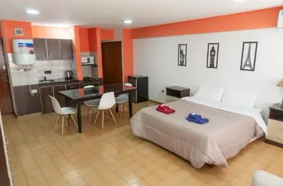 a bedroom with a bed and a table and a kitchen at Departamento Bv Chacabuco by INMOVE Temporarios in Cordoba