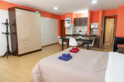 a bedroom with a large bed and a kitchen at Departamento Bv Chacabuco by INMOVE Temporarios in Cordoba