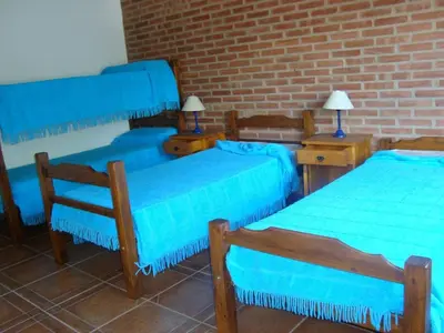 three blue beds in a room with a brick wall at Duplex de la Virgen in Mina Clavero