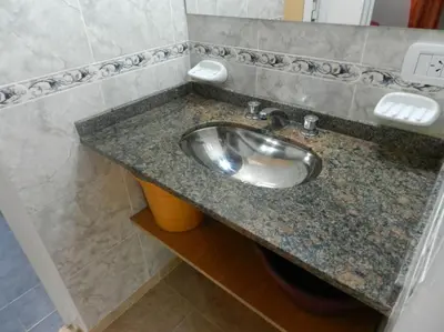a bathroom sink with a granite counter top at Duplex de la Virgen in Mina Clavero