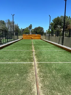 a tennis court with green grass on it at departamento complejo Veneto Village con vista al lago in Villa Parque Siquiman