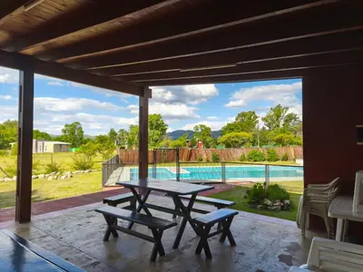 a patio with a table and benches and a pool at Paraíso Serrano 6 in Villa Ciudad Parque
