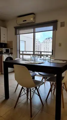 a dining room table with chairs and a large window at Departamento Quirós in Cordoba