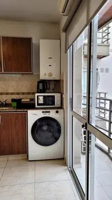a kitchen with a washing machine and a microwave at Departamento Quirós in Cordoba