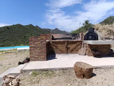 a outdoor grill with a wooden gate and a wooden stump at La Deseada in Quines