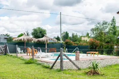 a pool with a table and chairs and a fence at Cabañas Aires De Luna in Los Reartes