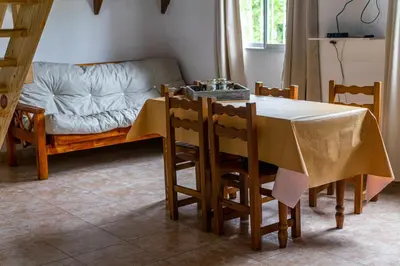 a dining room with a table and a couch at Cabañas Aires De Luna in Los Reartes
