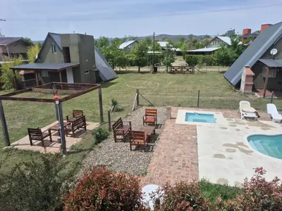 a backyard with a pool and chairs and a house at Cabañas Aires De Luna in Los Reartes