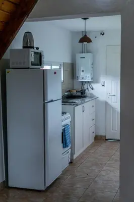 a kitchen with a white refrigerator and a stove at Cabañas Aires De Luna in Los Reartes