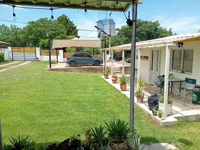 a house with a yard with a car in the background at Cabañas cochico in Villa Carlos Paz