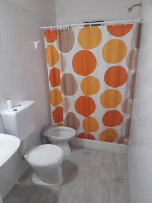 a bathroom with a toilet and a shower curtain at Cabañas cochico in Villa Carlos Paz