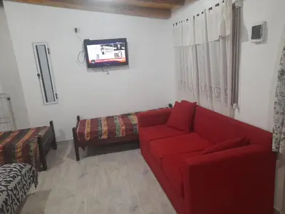 a living room with a red couch and a tv at Cabañas cochico in Villa Carlos Paz