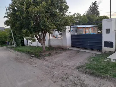 a garage with a blue gate next to a tree at Cabañas cochico in Villa Carlos Paz
