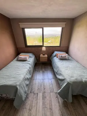 two twin beds in a room with a window at Cuatro Soles in Villa Yacanto