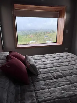 a bedroom with a bed with pillows and a window at Cuatro Soles in Villa Yacanto