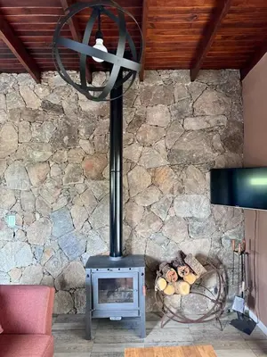 a stove in a living room with a stone wall at Cuatro Soles in Villa Yacanto