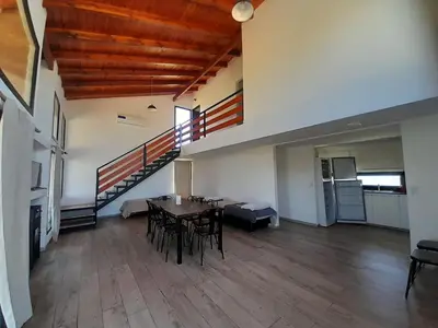 a room with a table and chairs and a staircase at Cabañas Altos de Kamiâre in Villa Yacanto