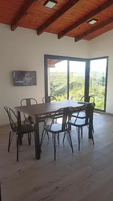 a table and chairs in a room with a large window at Cabañas Altos de Kamiâre in Villa Yacanto
