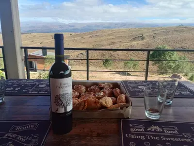 a bottle of wine and a box of pastries on a table at Cabañas Altos de Kamiâre in Villa Yacanto