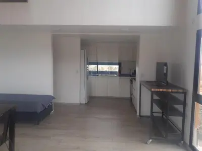 a bedroom with a bed and a kitchen in it at Cabañas Altos de Kamiâre in Villa Yacanto