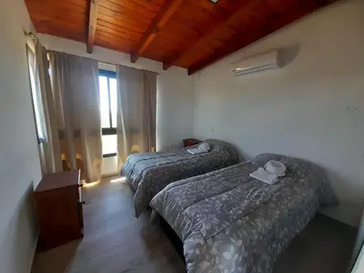 a hotel room with two beds and a window at Cabañas Altos de Kamiâre in Villa Yacanto