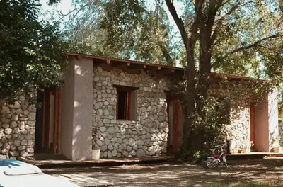 a stone house with a tree in front of it at Las cuatro estaciones in Merlo
