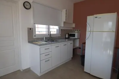 a kitchen with white cabinets and a white refrigerator at Apart Loma Linda in Merlo