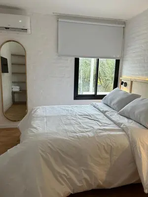 a bedroom with a large white bed and a mirror at Duplex en el Cerro de Las Rosas by Lugar in Cordoba