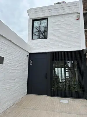 a white house with a black garage door at Duplex en el Cerro de Las Rosas by Lugar in Cordoba